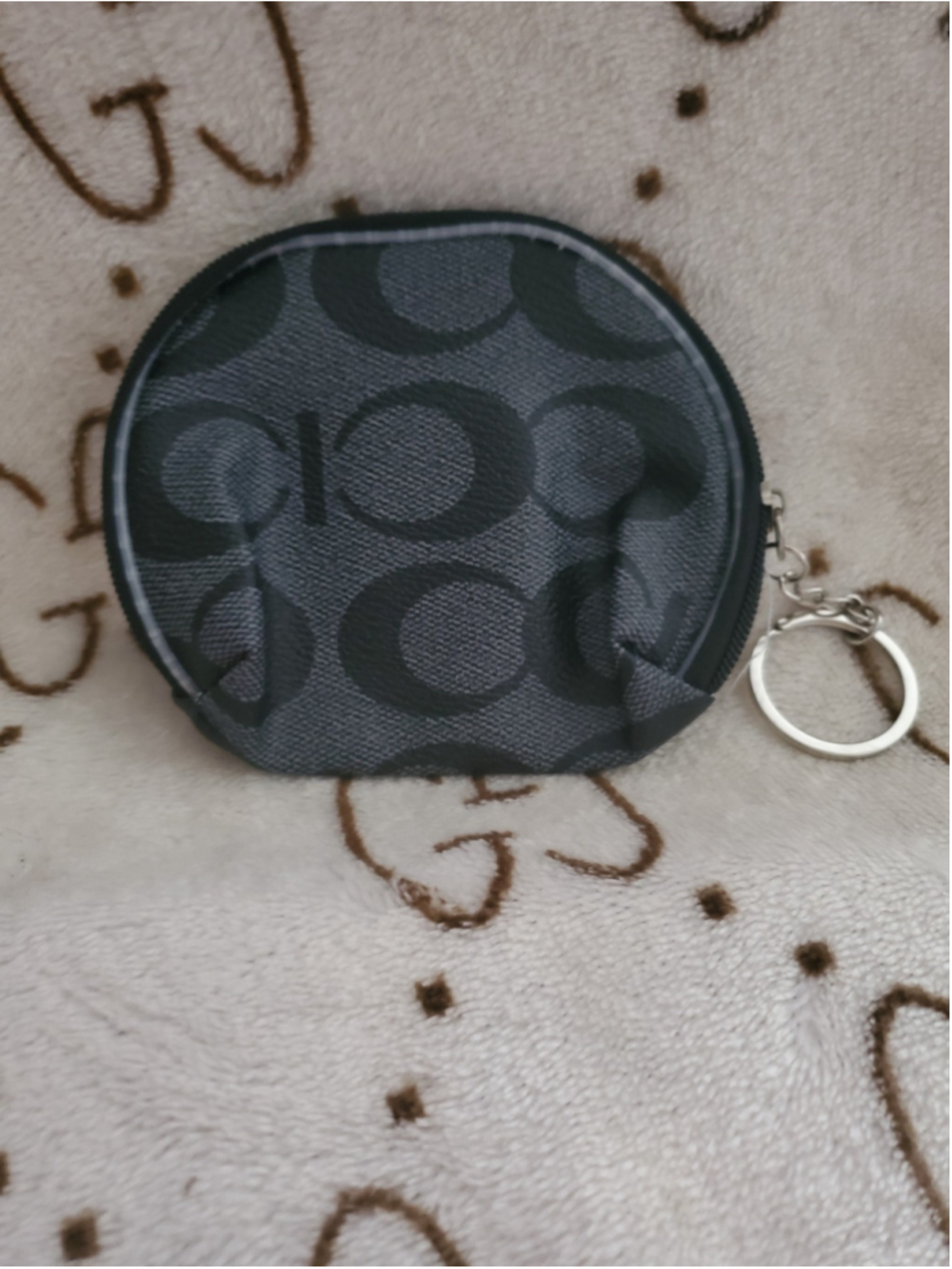 Miini coin pouch features a circular silhouette with a black and grey monogram
